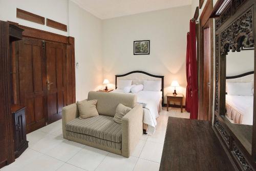 una camera con letto, sedia e specchio di Ndalem Maharani Guest House a Yogyakarta