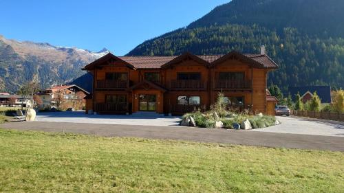 a large log cabin with mountains in the background at Tauern Appartements in Mallnitz