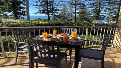 a black table with food and orange juice on a balcony at Flinders Lodge Unit 1 in Yamba