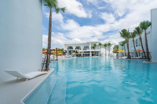 una piscina en un complejo con una silla y palmeras en The Gems Mining Pool Villas Pattaya en Nong Prue