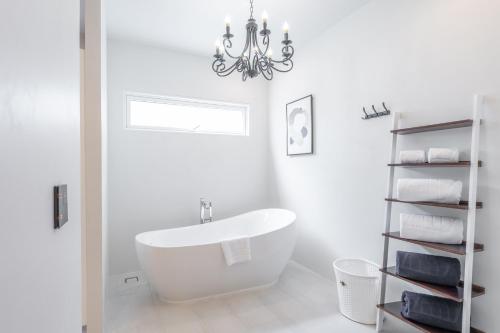 a white bathroom with a tub and a chandelier at The Gems Mining Pool Villas Pattaya in Nong Prue
