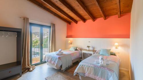 twee bedden in een kamer met een oranje muur bij Countryhouse Bradomín Cártama by Ruralidays in Cártama