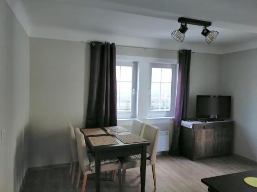 a dining room with a table and chairs and a television at Ferienwohnung H2 am Hainich 