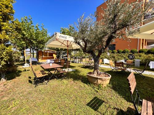 un tavolo da picnic con ombrellone e albero di Hotel Residence Loren - contact & contactless check-in a Uster