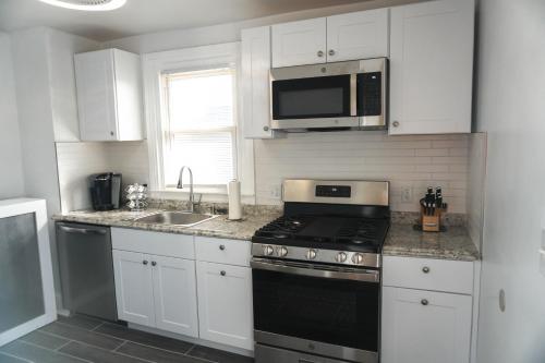 a kitchen with white cabinets and a stove and a microwave at Lincoln Manor - Newly Renovated, 1mile from PHL Airport and Sports Stadiums in Prospect Park