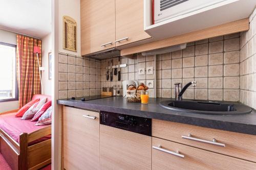 eine kleine Küche mit einem Waschbecken und einem Bett in der Unterkunft Stylish modern apartment for 4 by Avoriaz Chalets in Avoriaz