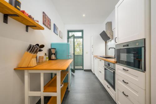 cocina con armarios blancos y encimera de madera en Modern Art Apartment, en Leipzig