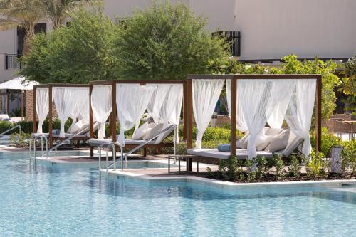 a row of lounge chairs next to a swimming pool at Jumeirah Gulf of Bahrain Resort and Spa in Manama