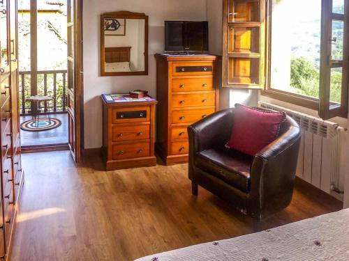 a living room with a leather chair and a dresser at Casa Rural Vely para 8 personas in Abándames