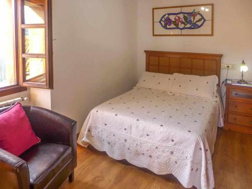 a bedroom with a bed and a leather chair at Casa Rural Vely para 8 personas in Abándames