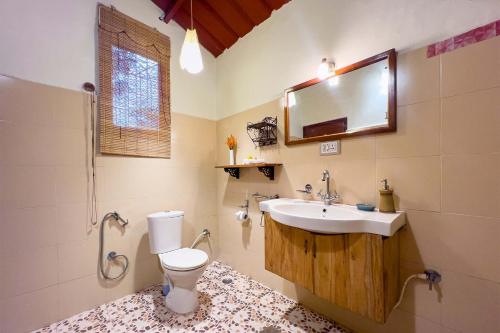 a bathroom with a toilet and a sink and a mirror at StayVista at Firefly By The River with Breakfast in Kushālnagar