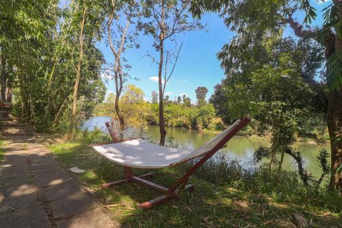una sedia seduta sul fianco di un fiume di StayVista at Firefly By The River with Breakfast a Kushalnagar