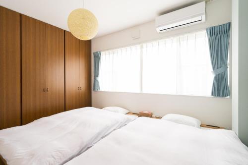 a bedroom with two white beds and a window at Aica TABI-NE in Kanazawa