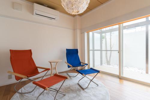 2 sillas y una mesa en una habitación con ventana en Aica TABI-NE en Kanazawa