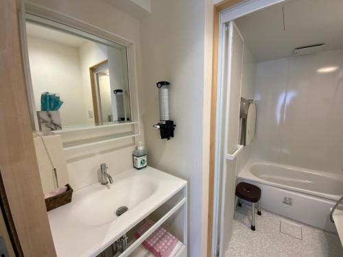 a bathroom with a sink and a mirror and a tub at オレンジの風 in Imabari