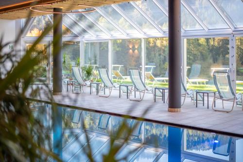 a conservatory with chairs and a table and a pool at Hotel Seehof in Monguelfo