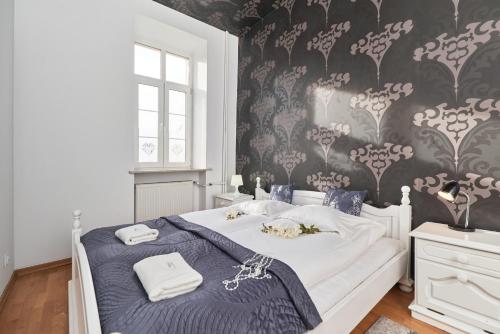 a bedroom with a bed and a wall with floral wallpaper at Rynek Apartment The Heart of the City by Renters in Wrocław