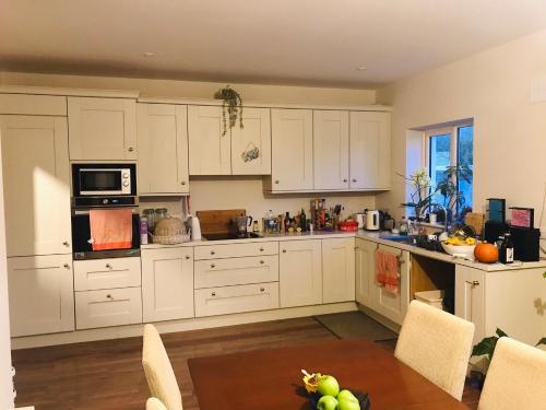 a kitchen with white cabinets and a table and chairs at Ensuite at the foot of Dublin Mountains in Dublin