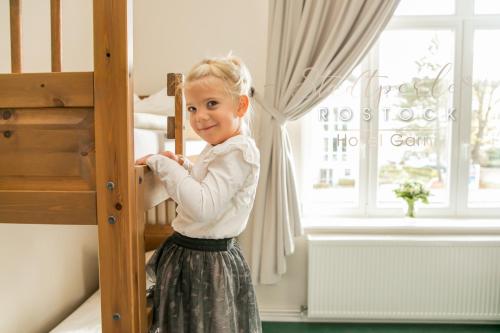 a little girl standing next to a bunk bed at Stadtperle Rostock in Rostock