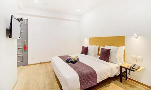 a bedroom with a large white bed with purple pillows at FabHotel Ashray Residency in Navi Mumbai