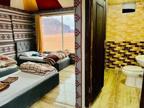 a room with three beds and a toilet and a window at Wadi Rum Cave Camp &Jeep Tour in Wadi Rum