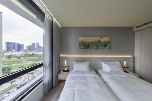 two beds in a room with a large window at CP Hotel in Dayuan