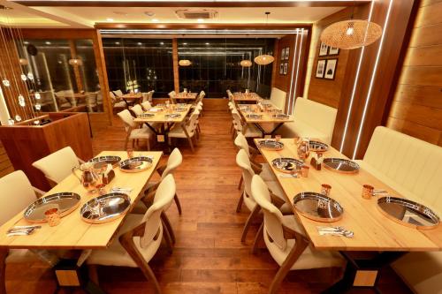 a restaurant with wooden tables and white chairs and tablesearcher at Wooden ECR Sea Resort in Puducherry