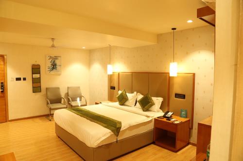 a bedroom with a bed and a desk and a chair at Hotel Reva Regency in Bhopal