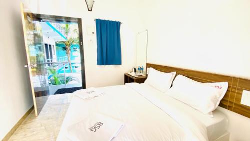 - une chambre avec un lit blanc et une porte coulissante en verre dans l'établissement BSG Stay - Turtle Beach Morjim Goa, à Morjim
