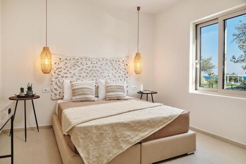een witte slaapkamer met een groot bed met 2 lampen bij Villa Danae Zante in Zakynthos