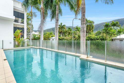 een zwembad in een huis met palmbomen bij Elysium Apartments in Palm Cove