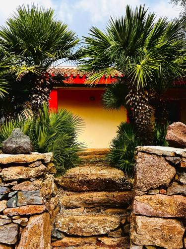 a house with palm trees and a stone wall at Agriturismo Conca' e Janas in Dorgali