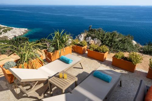 a patio with a table and chairs and the ocean at Joy Breeze in Kefallonia