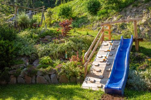 een blauwe glijbaan in een tuin met een heuvel bij Haidgerberhof - apartments & homemade food in Longostagno