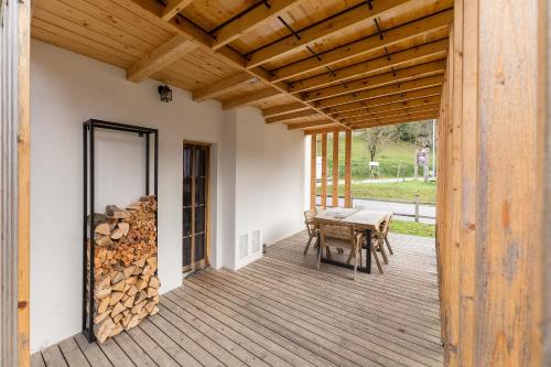 a wooden deck with a table and a pile of logs at Hiša na soncu / Sun house in Zgornje Gorje
