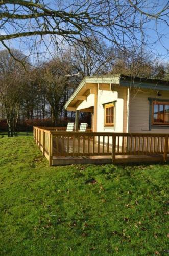 a house with a wooden deck in a yard at Stable Lodge in Drymen