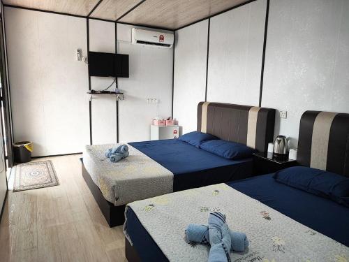 Cette chambre comprend 2 lits et une télévision. dans l'établissement Padang Besar Rainbow Cabin Homestay, à Padang Besar