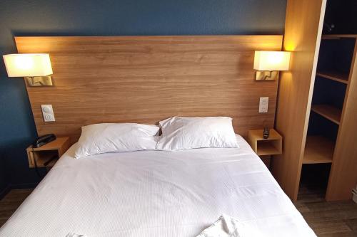 a bed with white sheets and pillows in a bedroom at The Originals Access, Hôtel les Iris, Berck-sur-Mer in Berck-sur-Mer