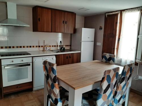 a kitchen with a wooden table and a white refrigerator at Hospital del Temple Casa Rural in Boquiñeni