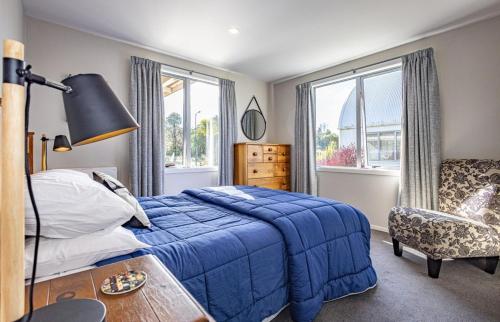 a bedroom with a blue bed and a chair at Ruapehu Retreat in National Park