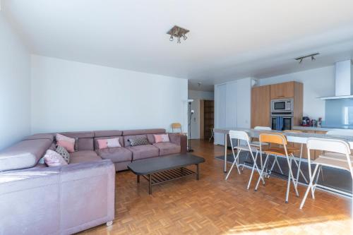 un salon avec un canapé et une table et une cuisine dans l'établissement La Nuit en Rose - 3 chambres - Balcon, à LʼHay-les-Roses