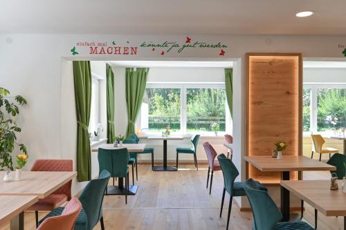 a restaurant with wooden tables and green chairs at Pension Freiheit in Pfronten