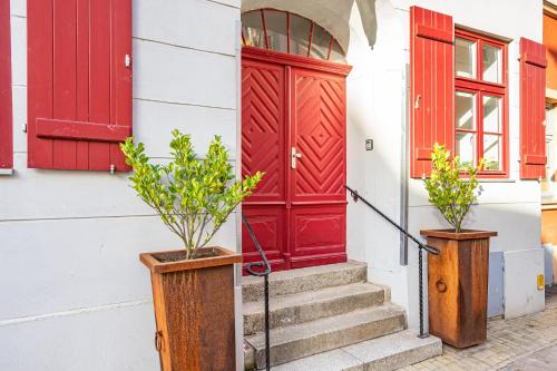 a red door and two potted plants in front of a building at Ferienwohnungen und Ferienhäuser Gohr in Stralsund