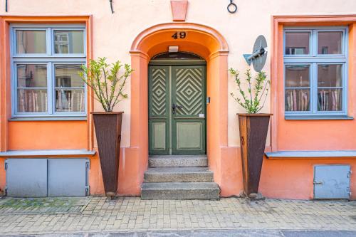 an orange building with a green door and two windows at Ferienwohnungen und Ferienhäuser Gohr in Stralsund