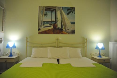 a bedroom with a green bed with two lamps at ARTEMIS ROOMS in Pefki
