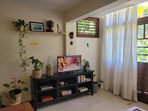 プライア・ド・フォルテにあるCasa Boha Praia do Forteのリビングルーム(本棚にテレビ付)