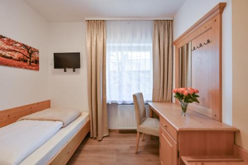 a bedroom with a bed and a desk and a window at Pension Freiheit in Pfronten