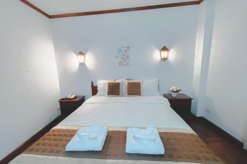 a bedroom with a large white bed with two shoes on it at khampiane hotel in Ban Nongdouang