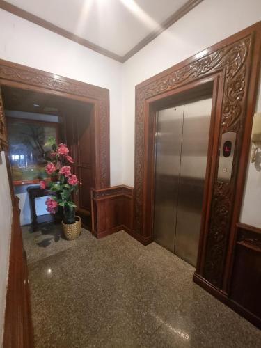 a hallway with a door and a vase with pink flowers at khampiane hotel in Ban Nongdouang