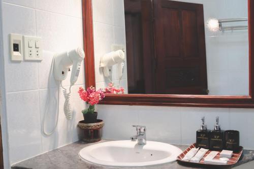 a bathroom sink with a mirror and a phone at khampiane hotel in Ban Nongdouang